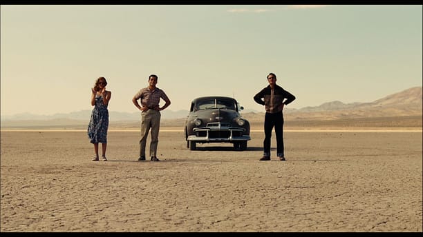 three people and a car on the desert