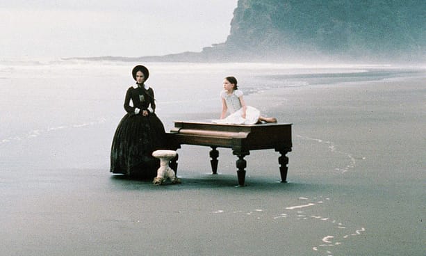 woman in a black dress and her daughter on the beach with piano